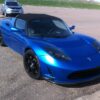 青いTesla Roadsterが屋外駐車場に停車している様子