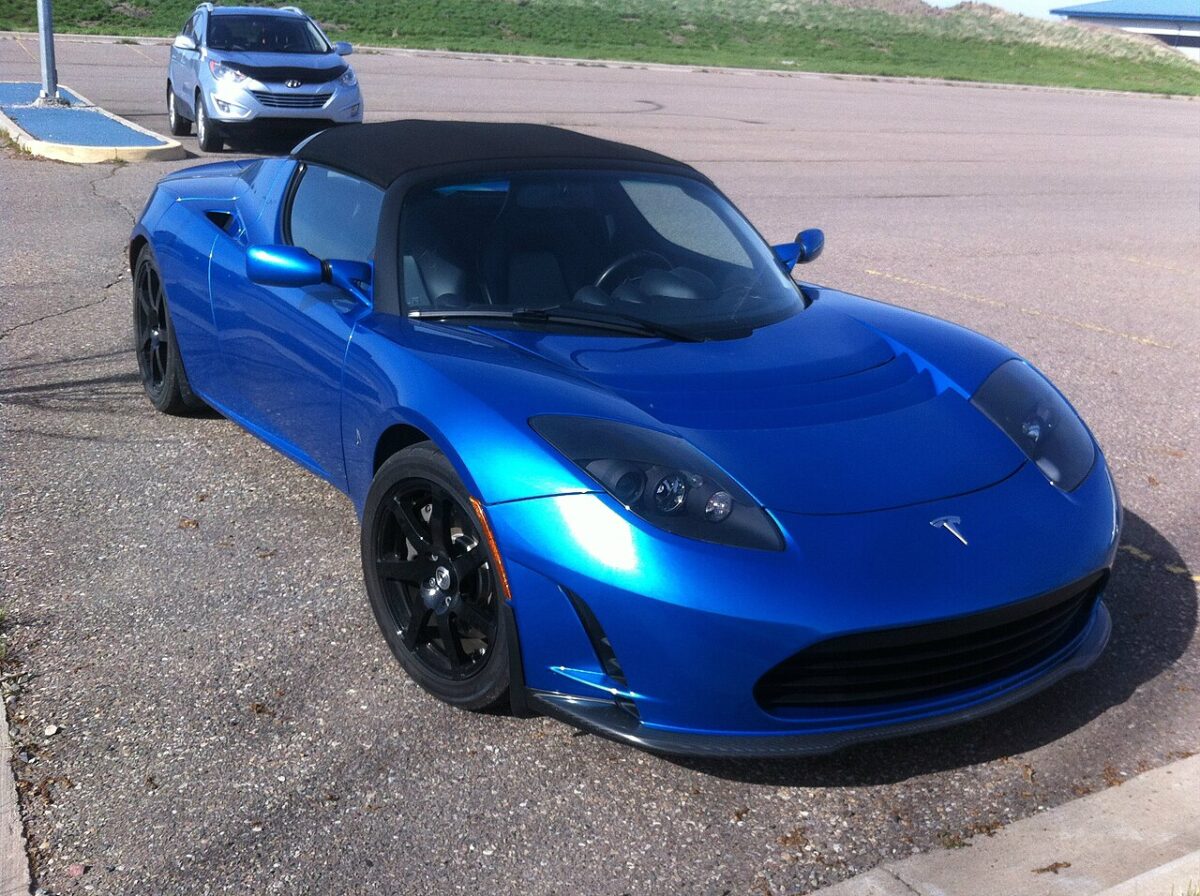 青いTesla Roadsterが屋外駐車場に停車している様子