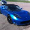 青いTesla Roadsterが屋外駐車場に停車している様子